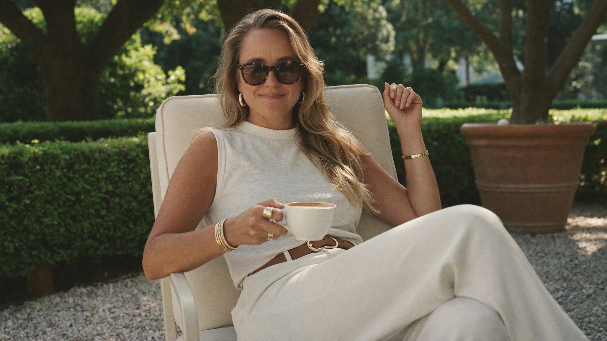 Christina seated in the garden with a cup in her hands.